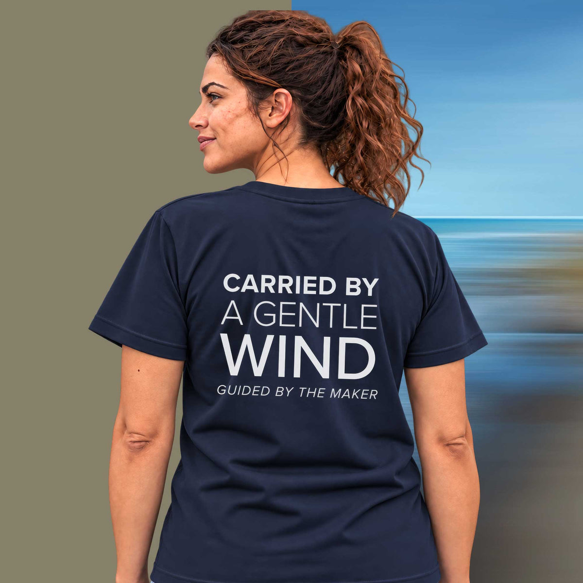 Model wearing the 'Carried by a gentle wind' back print tee in navy, large message printed on the back - Blend Designs NZ