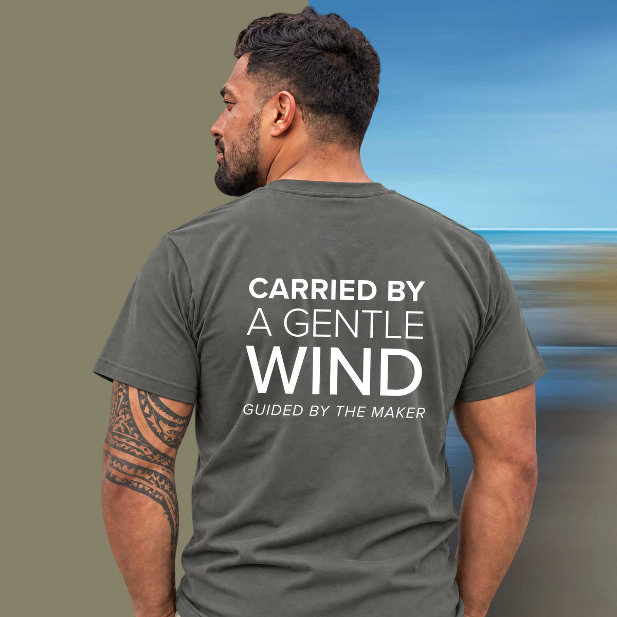 Model wearing the 'Carried by a gentle wind' back print tee in charcoal, large message printed on the back - Blend Designs NZ