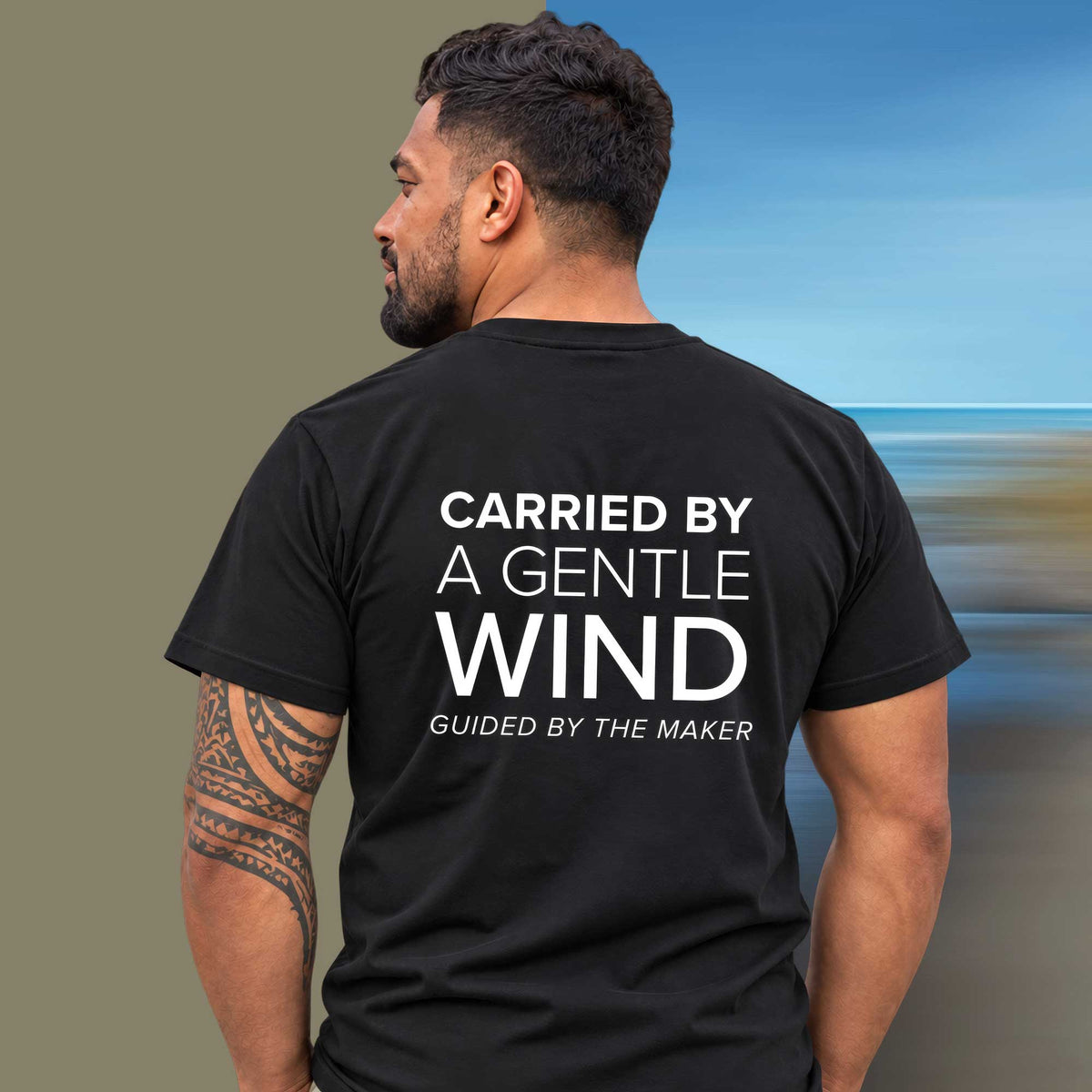 Model wearing the 'Carried by a gentle wind' back print tee in black, large message printed on the back - Blend Designs NZ