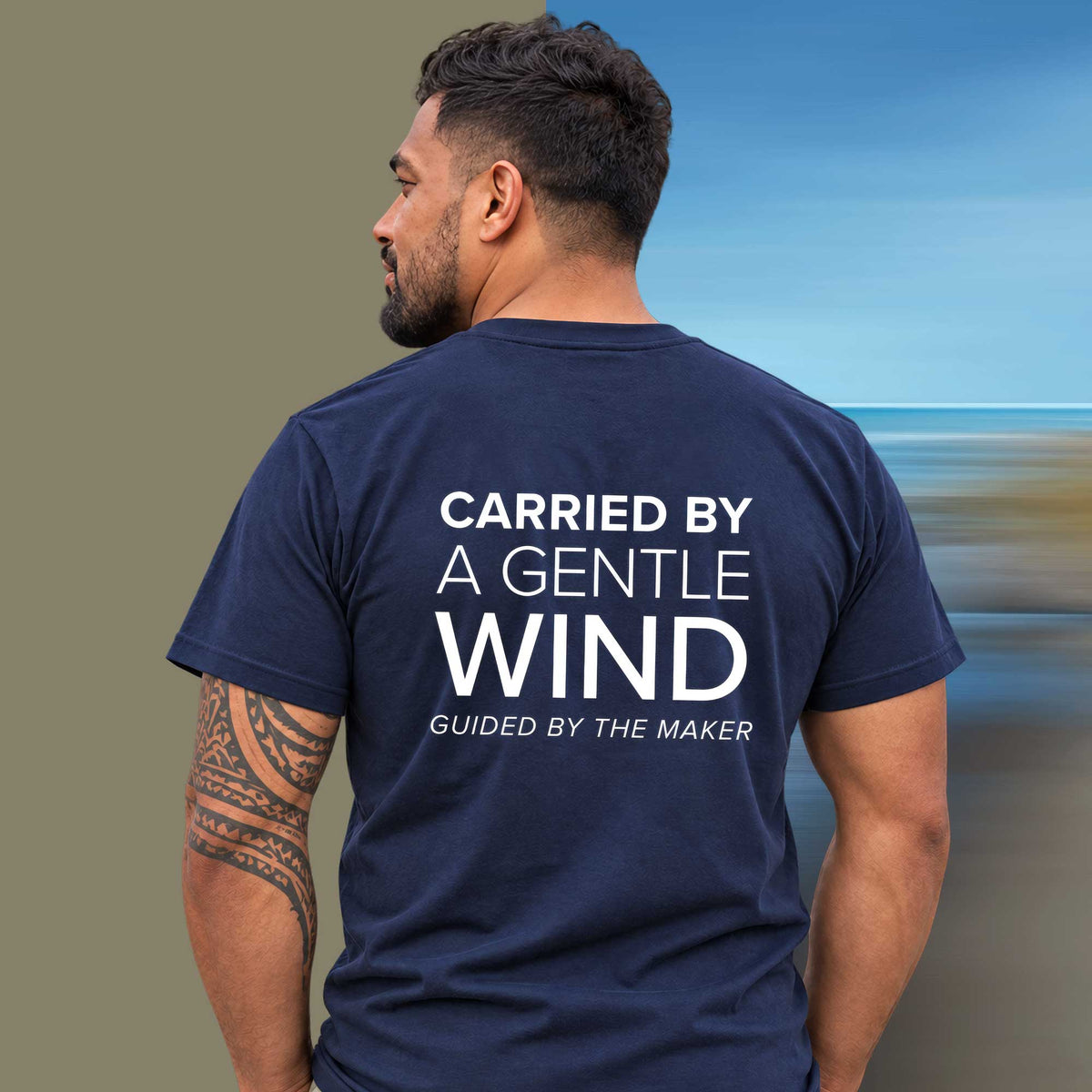 Model wearing the 'Carried by a gentle wind' back print tee in navy, large message printed on the back - Blend Designs NZ