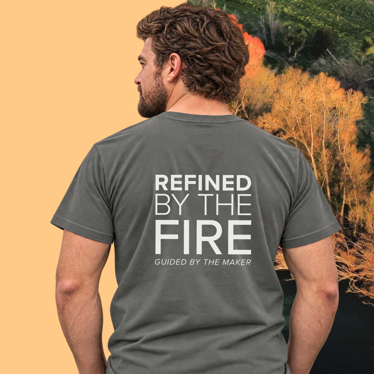 Model wearing the 'Refined by the fire' back print tee in charcoal, large message printed on the back - Blend Designs NZ