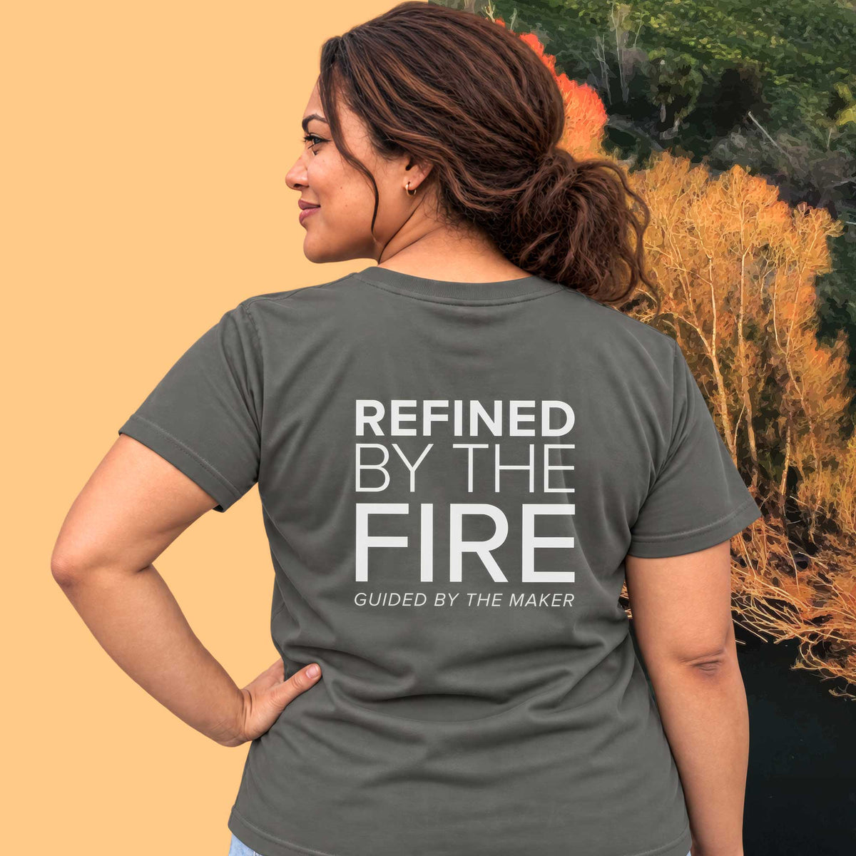 Model wearing the 'Refined by the fire' back print tee in charcoal, large message printed on the back - Blend Designs NZ