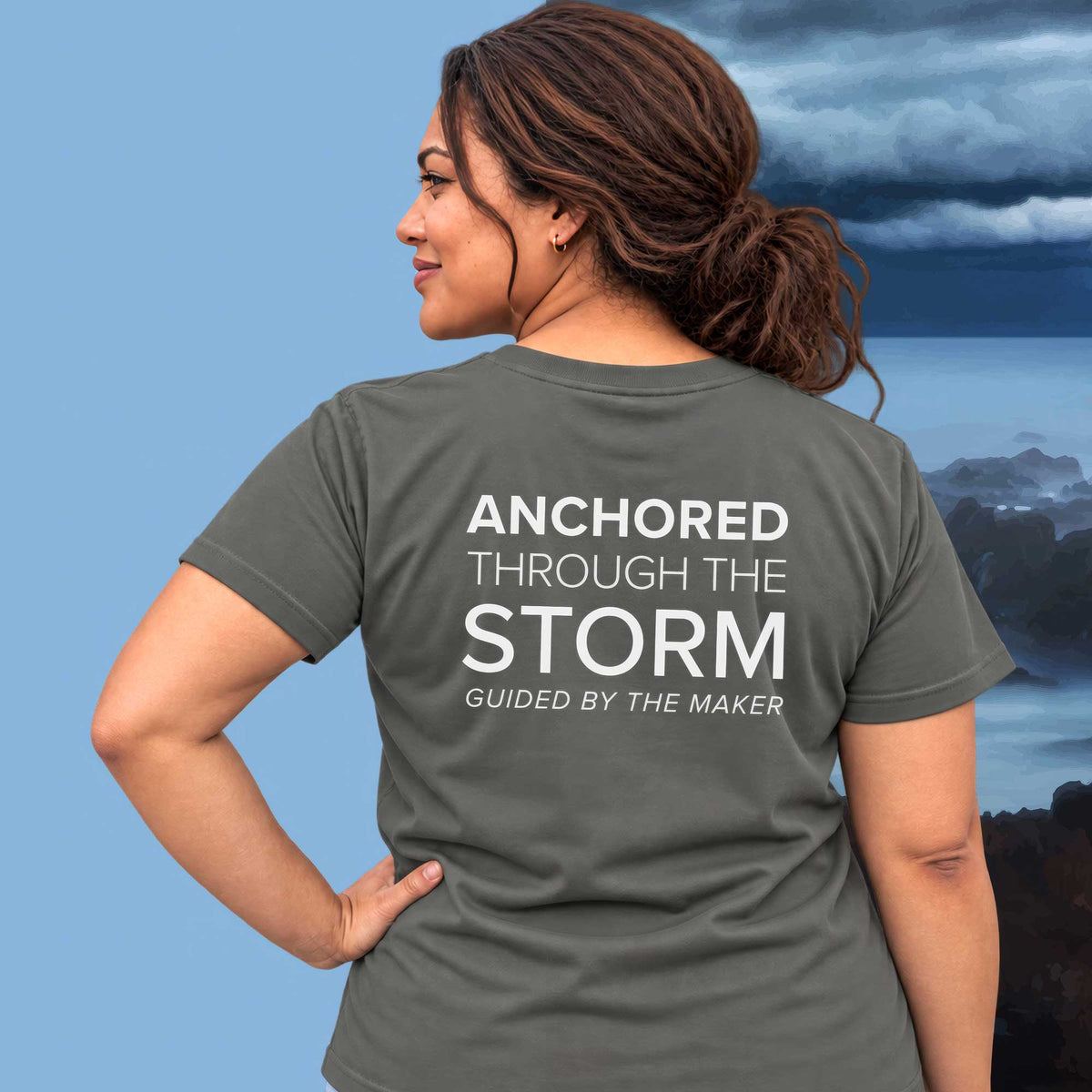 Model wearing the 'Anchored through the storm' back print tee in charcoal, large message printed on the back - Blend Designs NZ