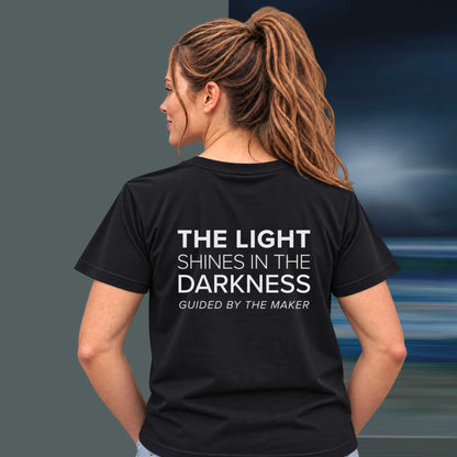 Model wearing the 'The light shines in the darkness' back print tee in black, large message printed on the back - Blend Designs NZ