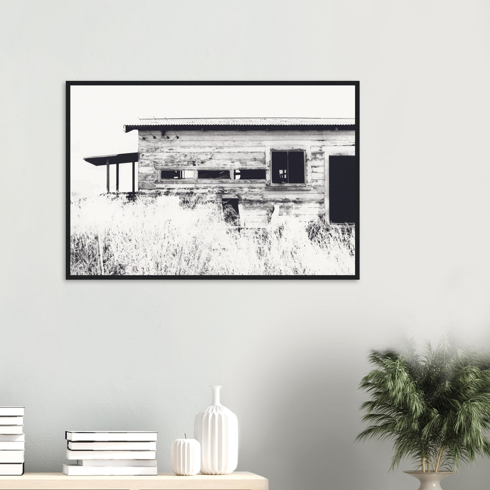 Old timber woolshed in black and white with peeling paint and wild grass in The Woolshed by NZ artist Ben Hart.
