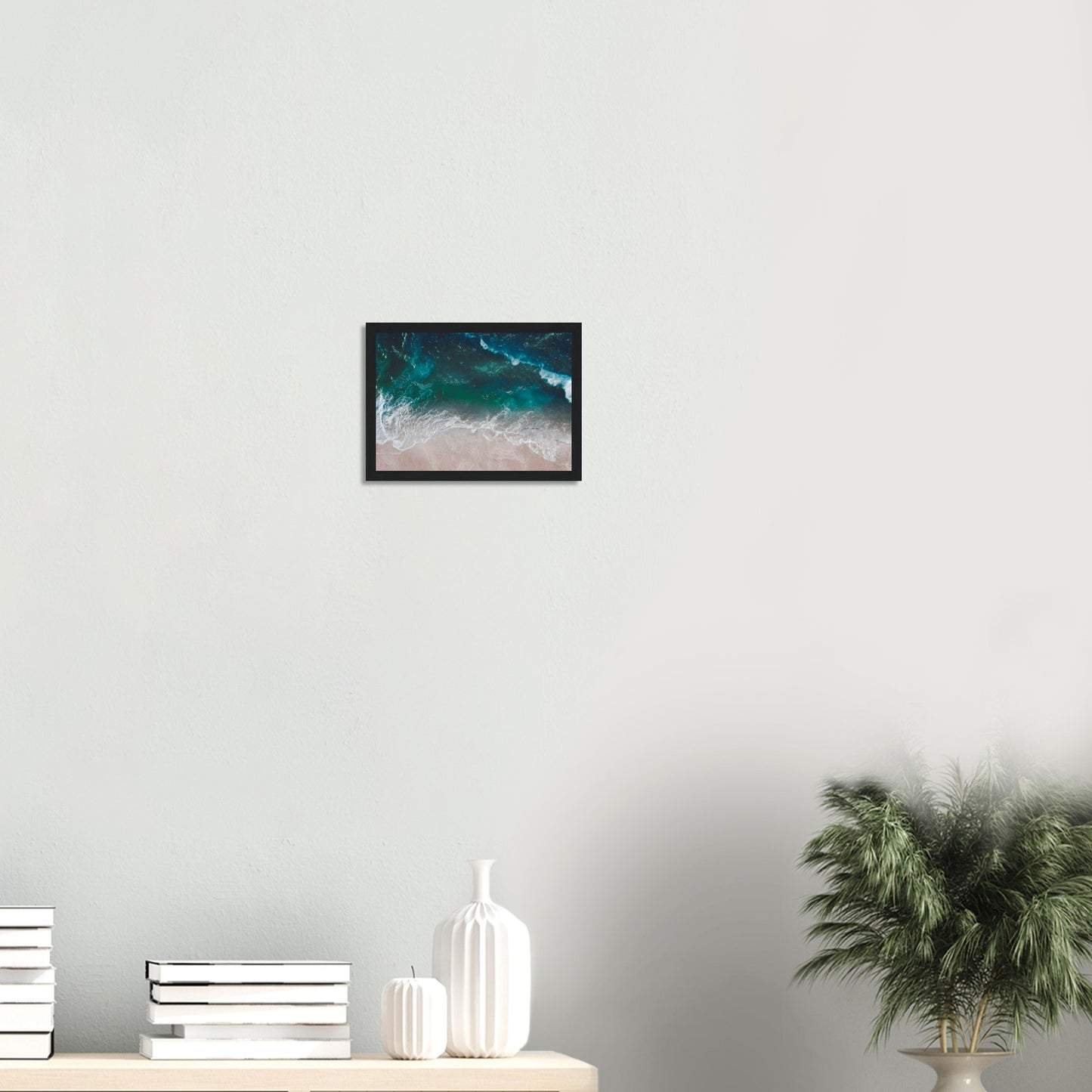 Aerial view of ocean waves rolling onto sand in teal and blue tones.