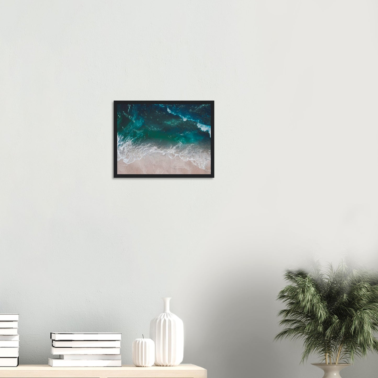 Aerial view of ocean waves rolling onto sand in teal and blue tones.