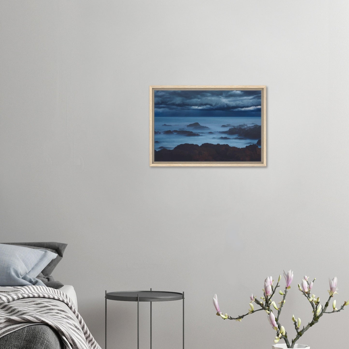 Deep navy and steel-blue tones sweep across a moody sky, while waves crash and swirl around jagged rocks, softened by a misty, dreamlike haze.