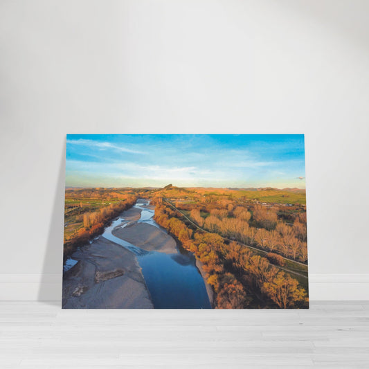 Aerial artwork of the Tukituki River winding through farmland, glowing in golden light with blue water reflections.