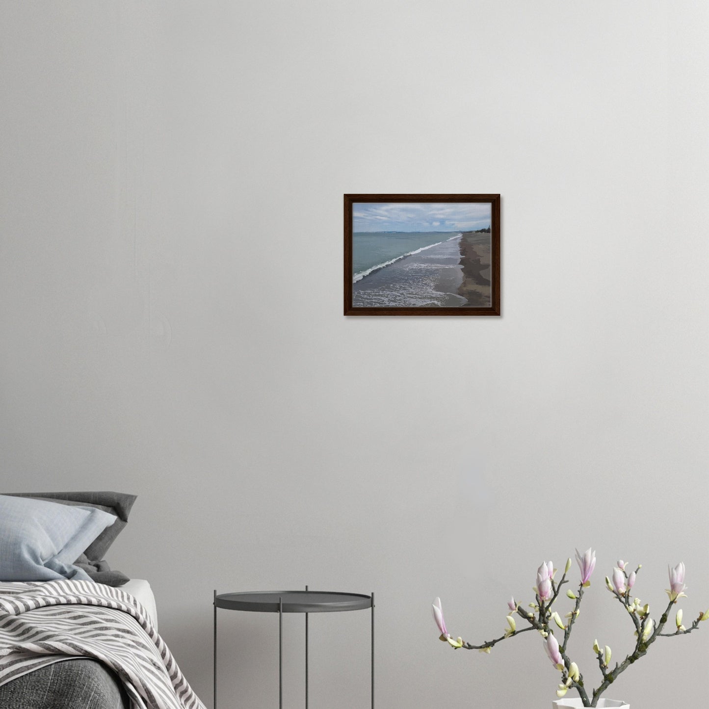 Gentle waves roll onto the dark sand, stretching endlessly into the distance under a softly clouded sky. Hints of pine trees and distant land complete the scene