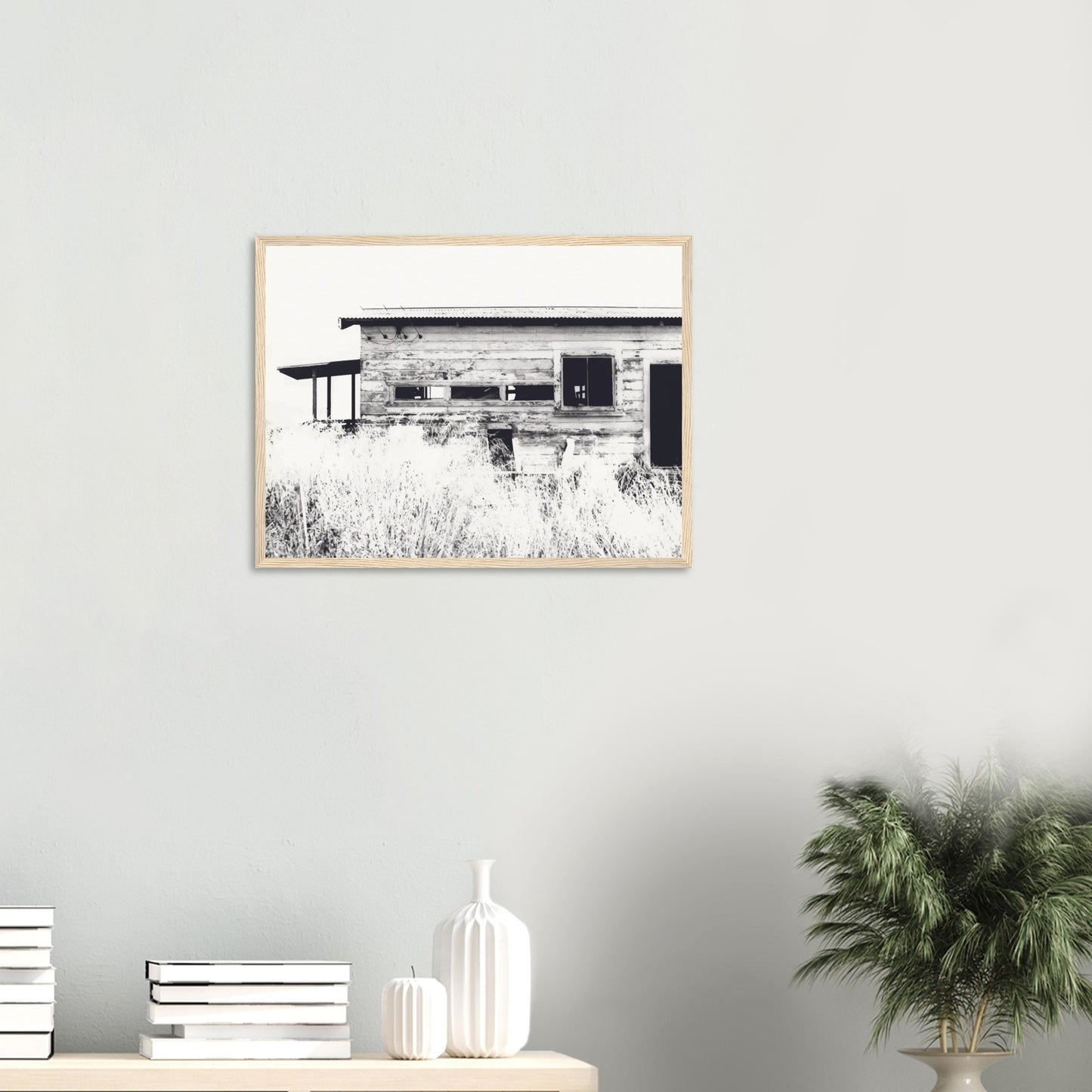 Old timber woolshed in black and white with peeling paint and wild grass in The Woolshed by NZ artist Ben Hart.