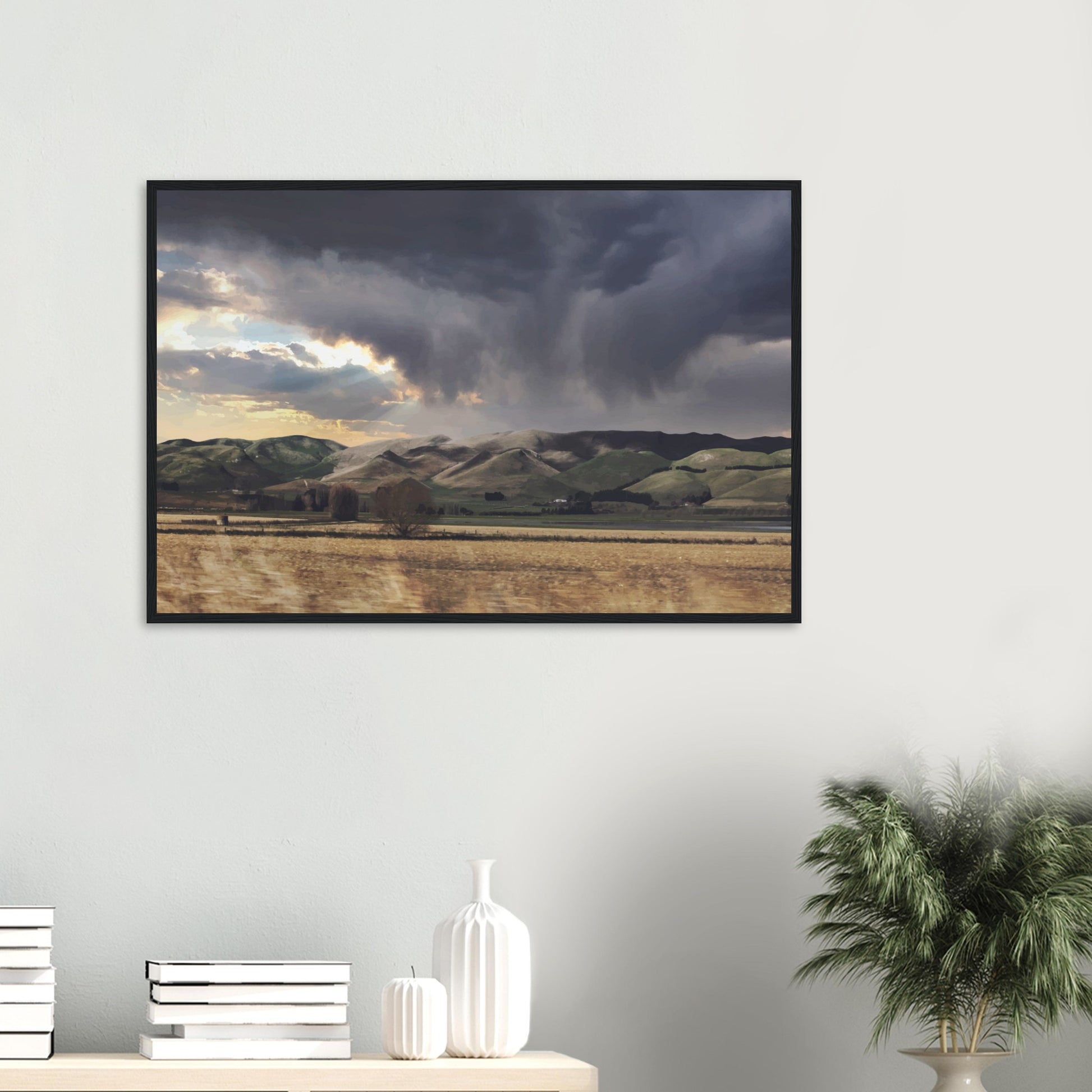 Landscape artwork of Te Hauke hills under dark clouds with beams of light breaking through.
