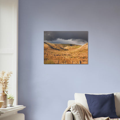 Golden Hawke’s Bay hills beneath dark clouds in a nostalgic NZ landscape artwork titled Trip Home by Ben Hart.