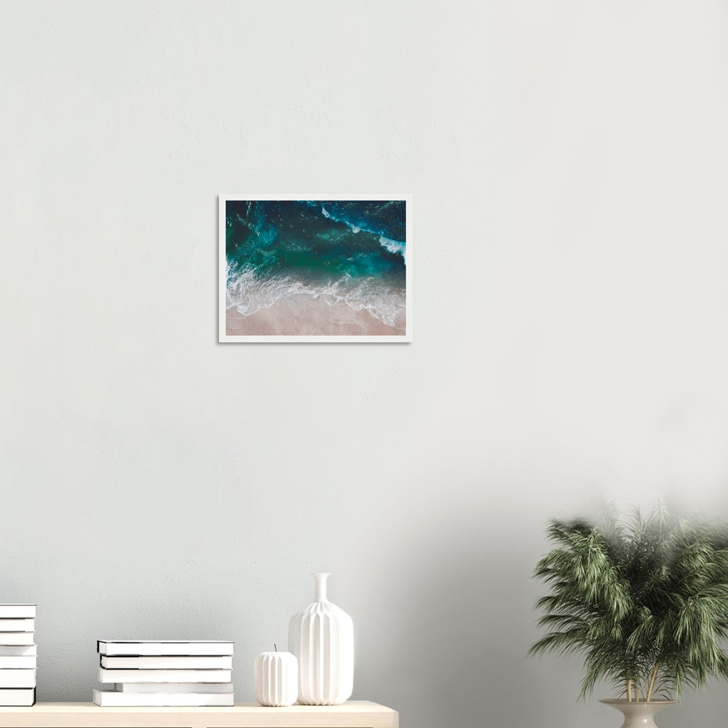 Aerial view of ocean waves rolling onto sand in teal and blue tones.