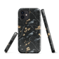 Dark phone case with blackbirds and gold blossoms on black branches.