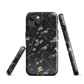Dark phone case with blackbirds and gold blossoms on black branches.