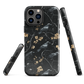 Dark phone case with blackbirds and gold blossoms on black branches.