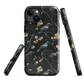 Dark phone case with blackbirds and gold blossoms on black branches.