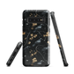 Dark phone case with blackbirds and gold blossoms on black branches.