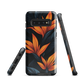 Phone case with bold orange bird of paradise flowers on dark background.