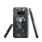 Gothic phone case with a floral skull design in grey tones, featuring white blossoms and dark detailing.