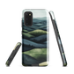 Phone case with layered mountain and forest landscape in blue and green hues
