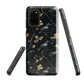 Dark phone case with blackbirds and gold blossoms on black branches.