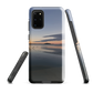 Phone case with tranquil lake scene at sunrise and distant hills.