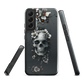 Gothic phone case with a floral skull design in grey tones, featuring white blossoms and dark detailing.