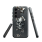 Gothic phone case with a floral skull design in grey tones, featuring white blossoms and dark detailing.
