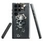 Gothic phone case with a floral skull design in grey tones, featuring white blossoms and dark detailing.