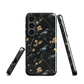 Dark phone case with blackbirds and gold blossoms on black branches.