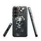 Gothic phone case with a floral skull design in grey tones, featuring white blossoms and dark detailing.