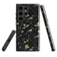 Dark phone case with blackbirds and gold blossoms on black branches.